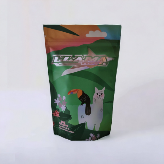 an image of our llama coffee bag with a cartoon llama with a toucan on the back of the llama. scenery of green hills and foliage and coffee plants framing the bottom of the picture   